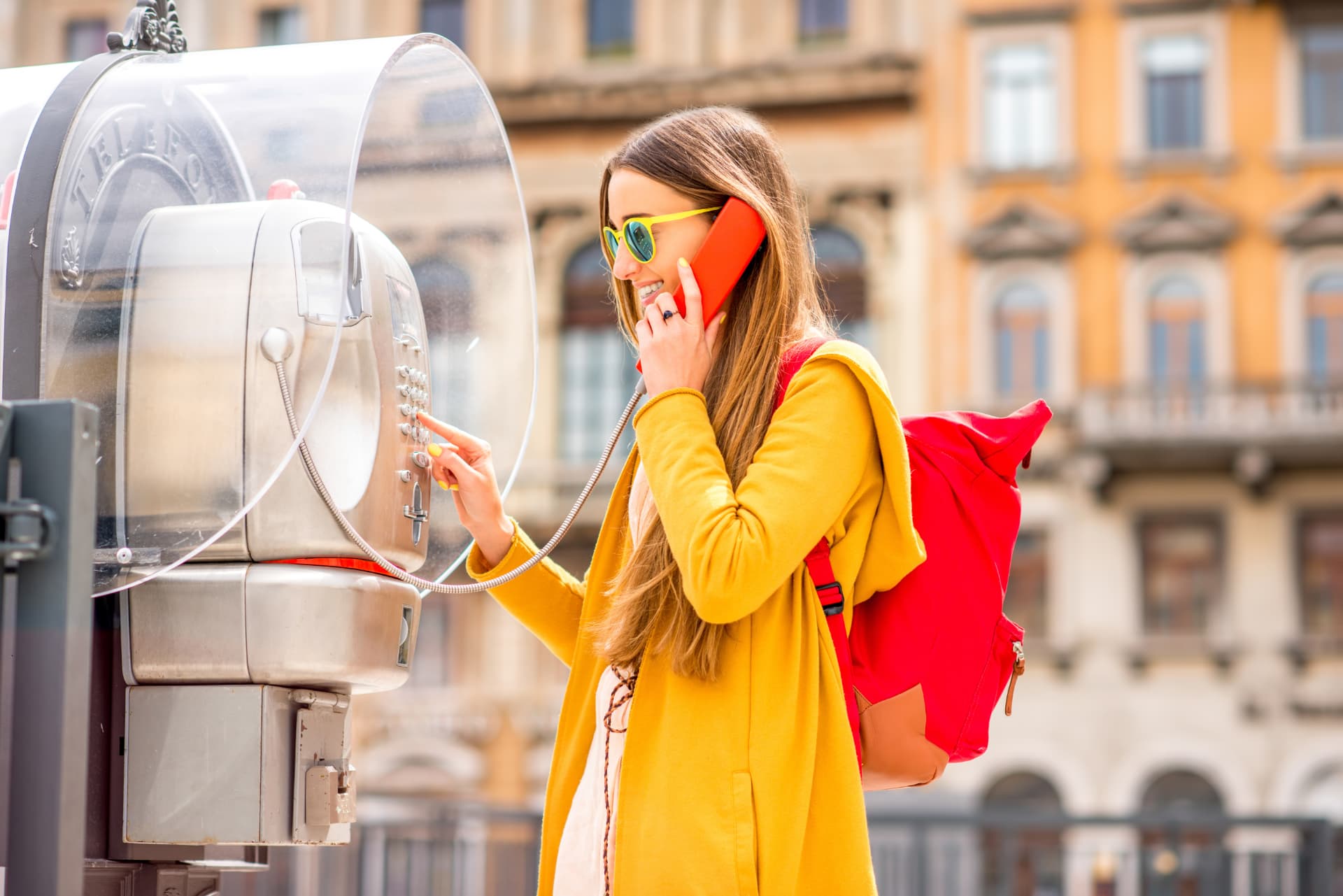 Traveler talking on a red telephone in an Italian square
