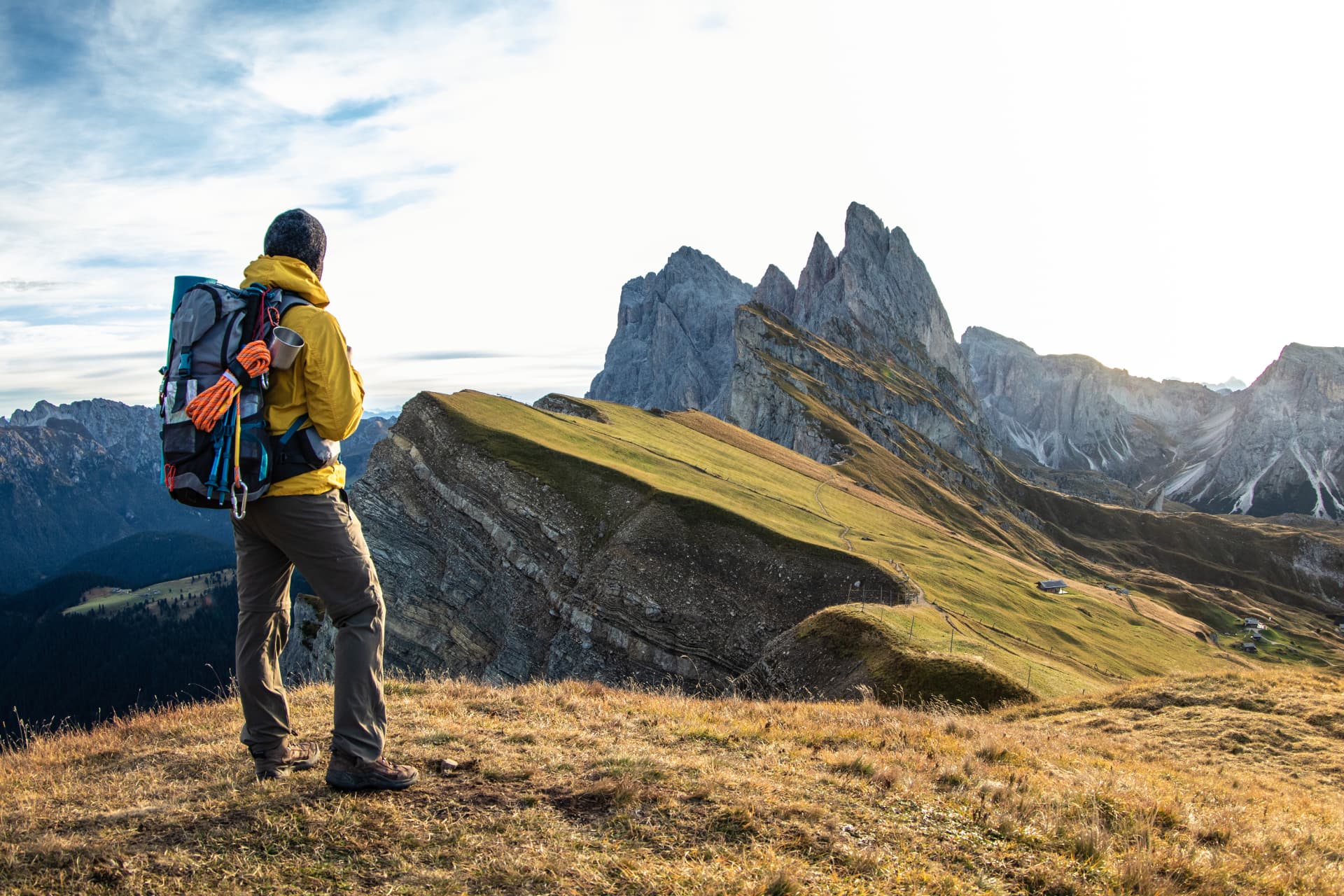 Hiker in a yellow jacket looking at the jagged peaks of the Brenta Dolomites