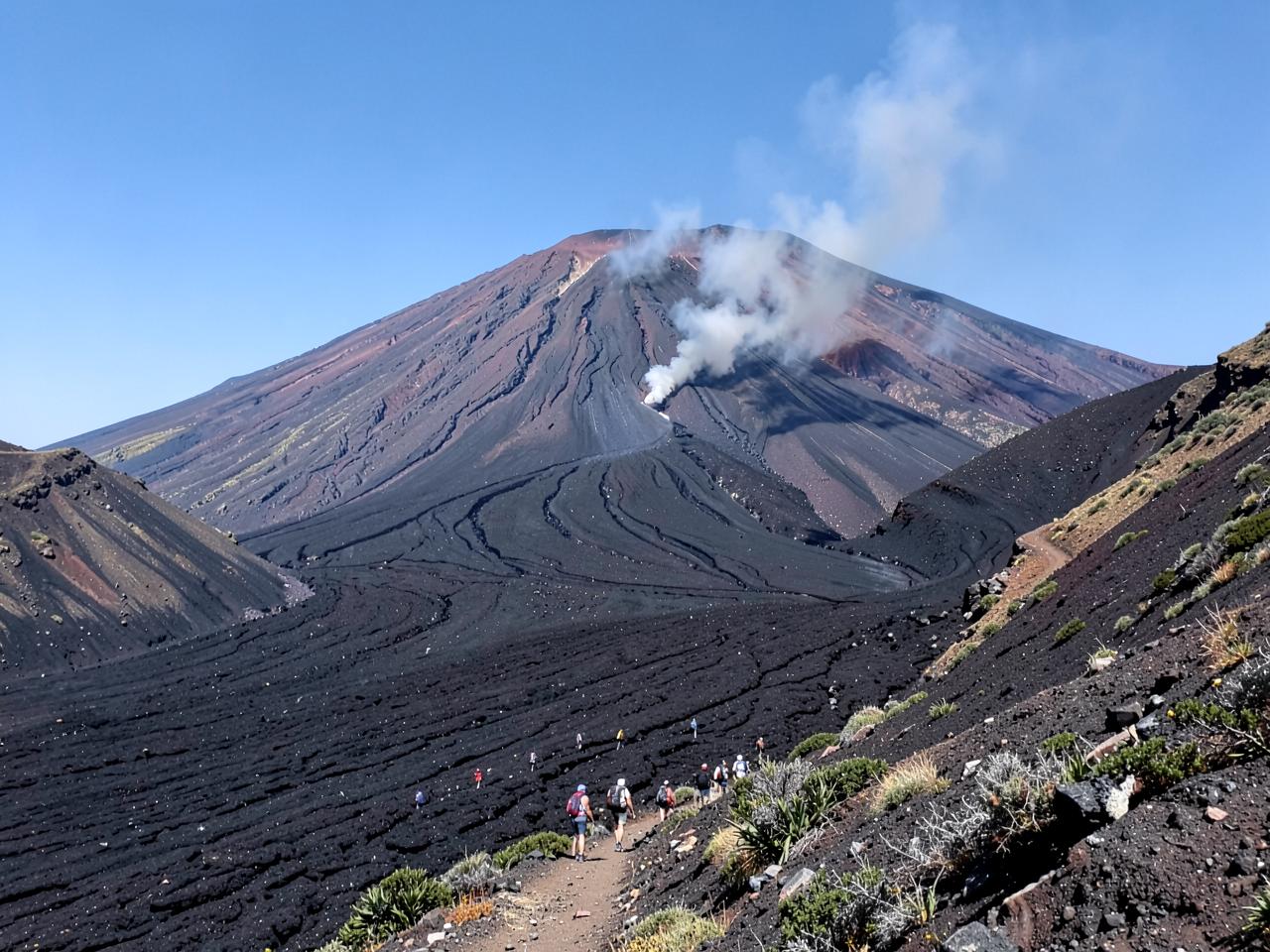 Hikers on the black lava slopes of Mount Etna